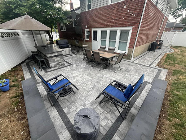 Backyard paver patio with outdoor kitchen and dining area