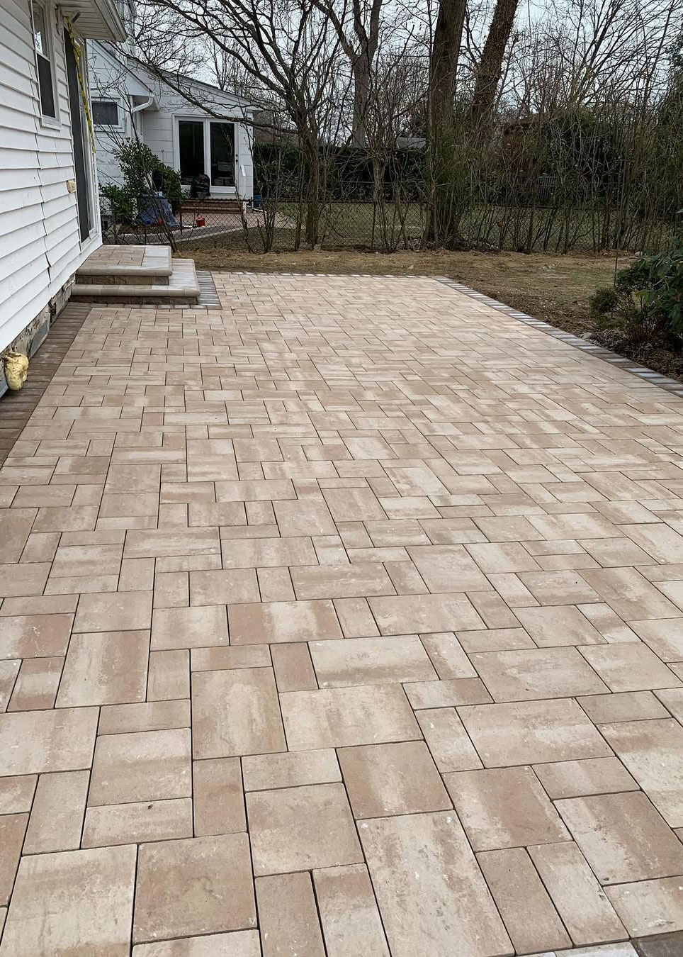 Large backyard paver patio with contrasting border