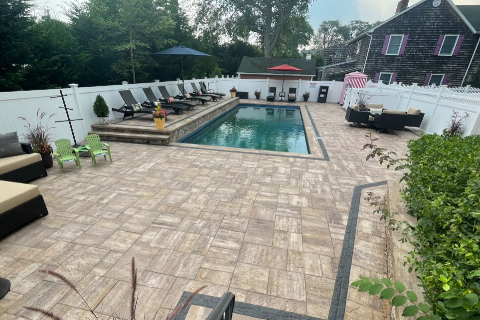 Custom paver pool patio surrounding an in-ground swimming pool