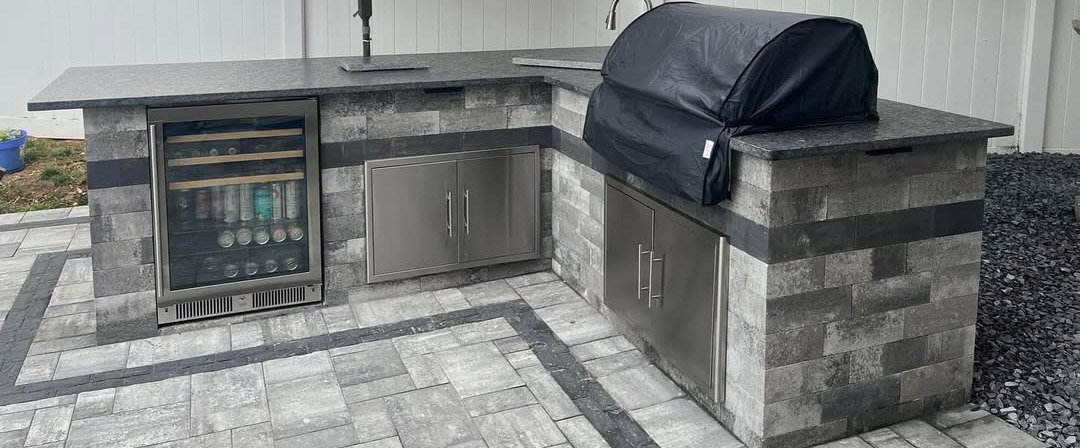 Custom outdoor kitchen with built-in grill, beverage fridge, and paver patio