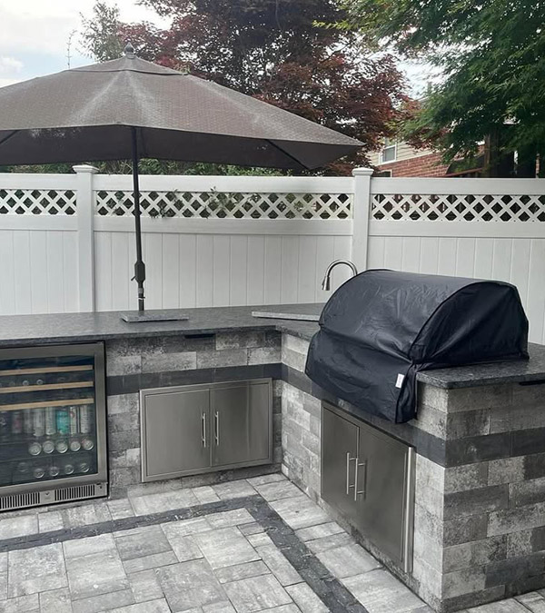 Outdoor kitchen with stone veneer, built-in grill, and paver patio